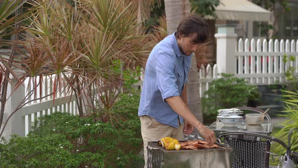 A Young Man Cooks Vegetables and Shrimps on a Barbeque in His Backyard alt
