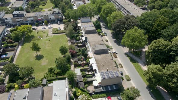 Aerial of row of houses near green park and a calm street in a suburban neighborhood alt