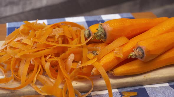 Pile of fresh, whole, raw, carrots and peels on a cutting board. alt