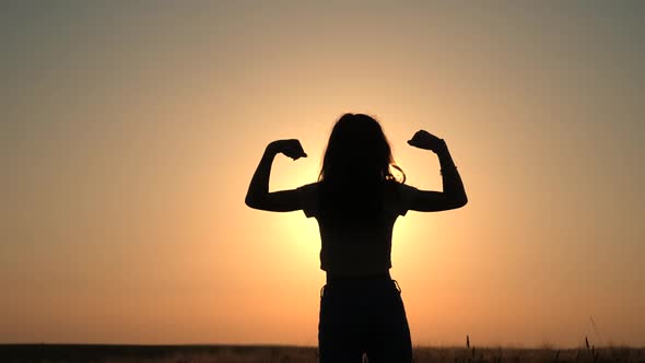 Strong girl, Winning, success , and life goals concept. Young woman with arms flexed facing the suns