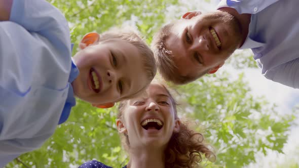 Bottom View of Lovely Family Looking Down at Camera and Laughing Outdoors alt
