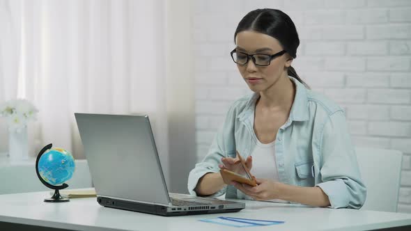 Asian Girl Entering Passport Data in Laptop Booking Tour at Travel Agency alt