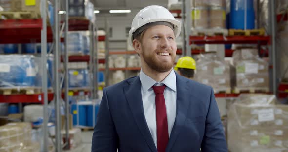 Portrait of Successful Young Manager Walking Among Shelves in Warehouse alt