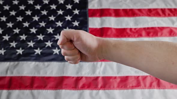 Thumbs Up and Thumbs Down Gestures Made with Caucasian Hand in Front of Blurry US Flag