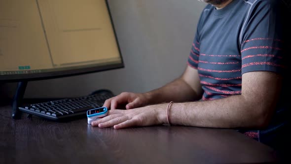 Pulse Oximeter in a Male Patient's Fingertip on Dark Wooden Table Background Medical Equipment alt