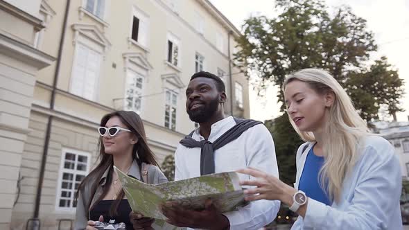 Happy Young People Walking on the Street with Beautiful Architecture and Exploring City Map alt