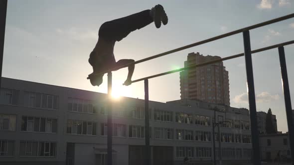 Silhouette of Male Gymnast Doing Push Ups in Handstand on Uneven Bars Outdoor alt
