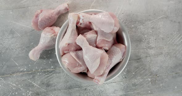 Bowl Full Raw Chicken Drumstick Slowly Rotates.  alt