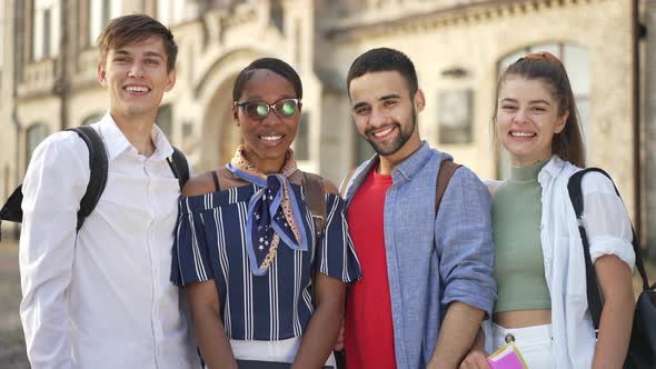 Medium Shot Four Happy Students Looking at Camera Smiling Showing Thumbs Up Simultaneously alt