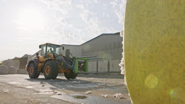 Large tractor loading cotton bales at a cotton gin before processing alt