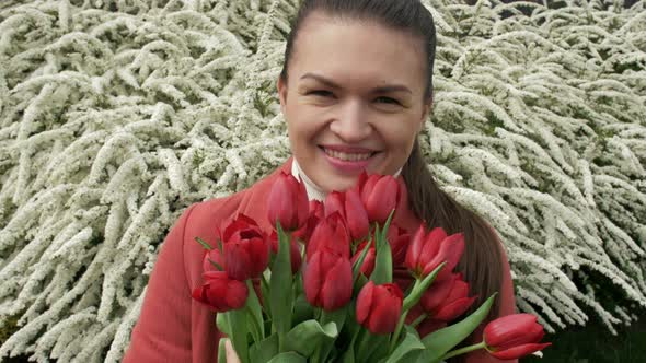 Portrait of a Happy Young Woman with a Bouquet of Red Tulips