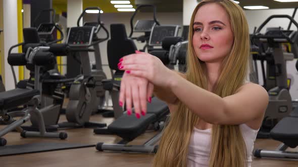A Young Beautiful Woman Stretches Her Hands in a Gym - Closeup alt