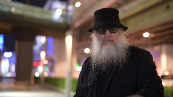 Mature Bearded Tourist Man Thinking in the City Streets at Night
