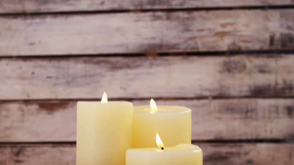 Close-up of burning candles with christmas decoration on wooden plank alt