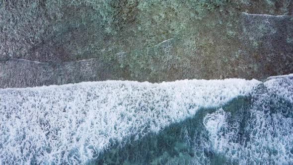 Aerial drone view of ocean waves washing over on a beach