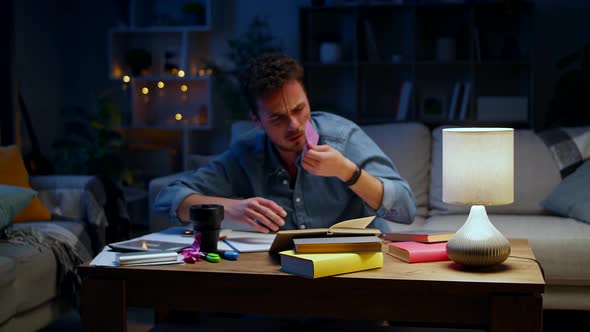 Young Man Fell Asleep on the Table While Studying at Home at Night alt