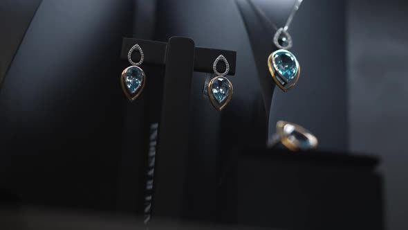 Earrings with Blue Gemstones Ring and Chain Hanging on Holder in Jewellery Store alt