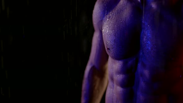 Muscular Abdomen of Sporty Man Standing in Rain in Darkness Closeup View of Washboard Abs alt
