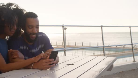 Couple using mobile phone in the beach alt