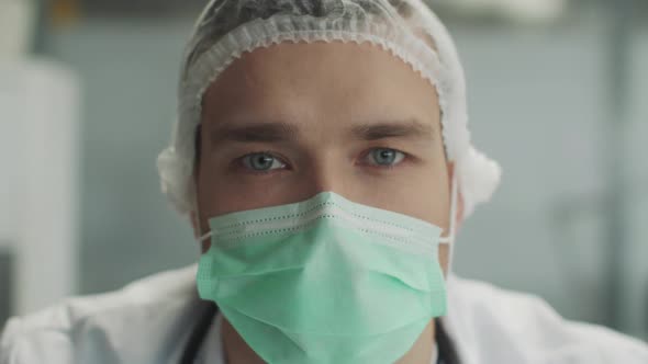 Closeup Portrait of an Infectious Disease Doctor in a Dressing Gown Medical Mask and Gloves alt