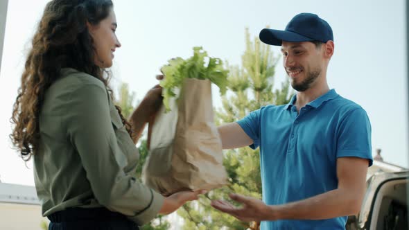 Female Customer Getting Organic Groceries From Male Courier and Paying with Smartphone alt