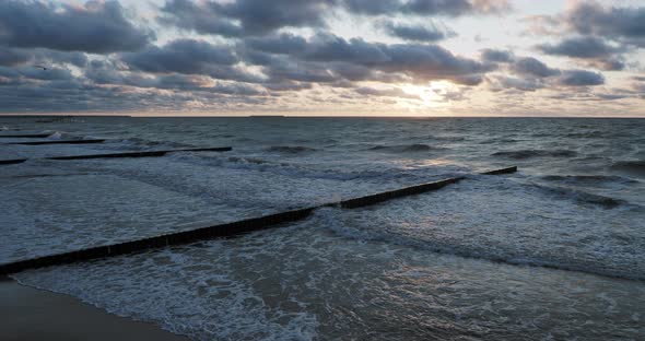 Breakwater of Larch Logs. Strengthening the Seashore To Keep the Sand on the Beach. Gorgeous Sunset alt
