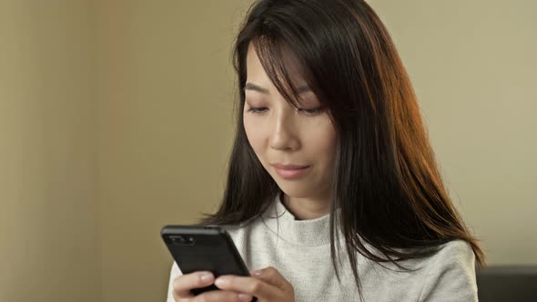 Portrait of a Young Asian Woman with a Mobile Phone in Her Hands
