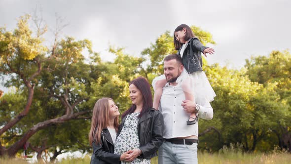 Young Parents with Two Kids Posing Among High Grass at Green Garden alt