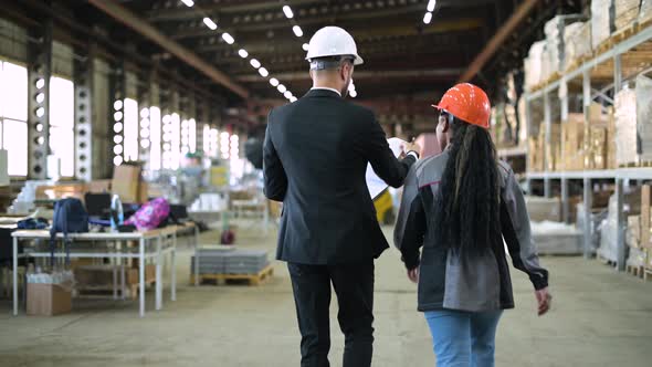 A young manager and a warehouse worker walk through the production workshop alt