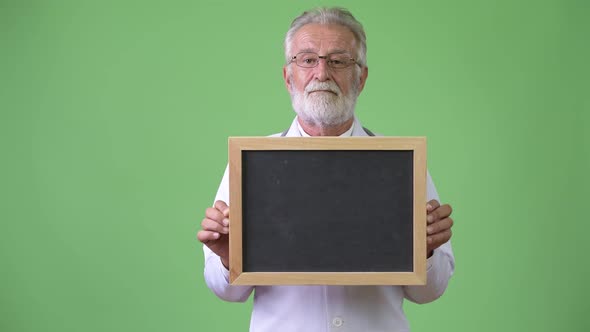 Handsome Senior Bearded Man Doctor Against Green Background alt