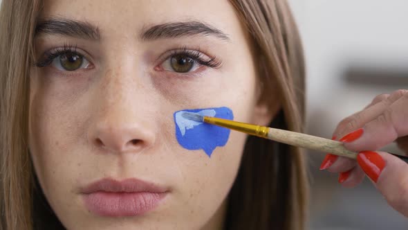 Close-up Portrait of Young Pleasant Woman Looking at Camera While Artist Painting Message Box alt