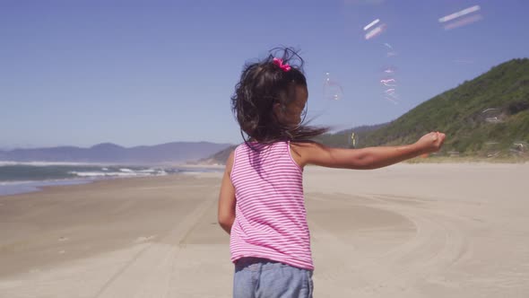 Young girl playing with bubbles at beach