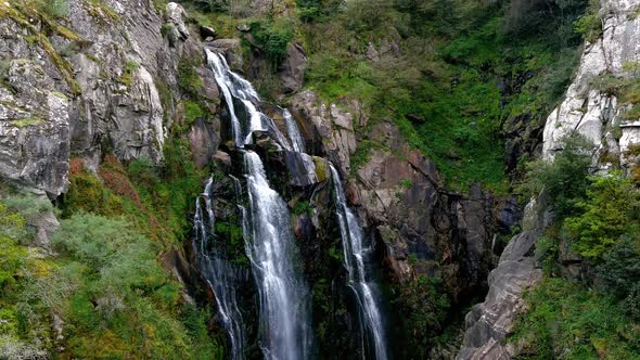 Aerial View Of Fervenza do Toxa Waterfalls Cascading Down Rockface. Pedestal Up, Tilt down Shot alt