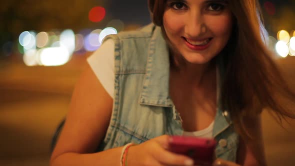 Teenage girl using smartphone outdoors at night