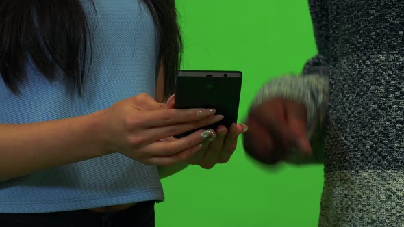 An Asian Woman and a Black Man Work on a Smartphone Together - Closeup - Green Screen Studio alt