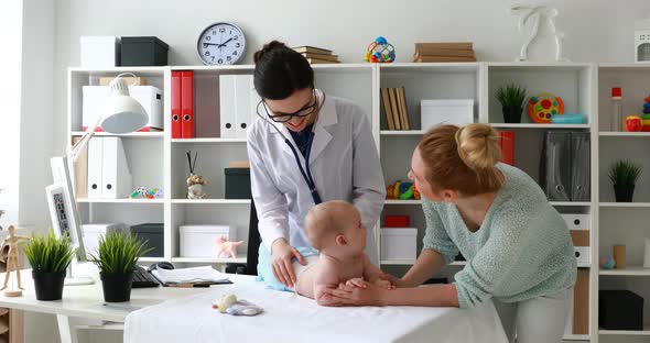 Doctor Giving Toy To Baby in White Room