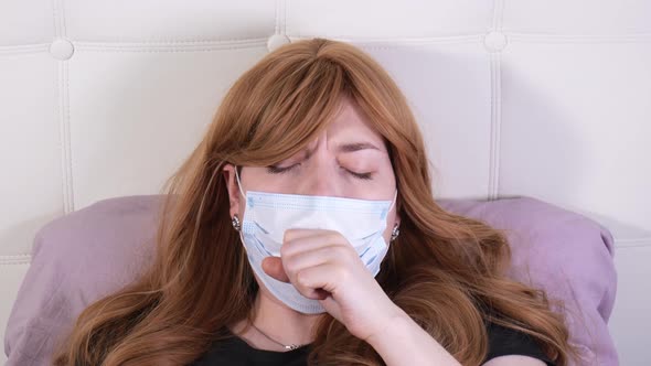 Girl in a Medical Mask Lying in Bed Coughs