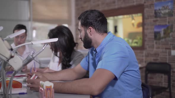Close-up of Tired Middle Eastern Dentistry Student Taking Head with Hands. Side View of Young Man alt