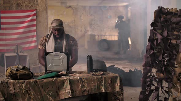 US Soldier Using Laptop, Radio at Makeshift Base alt