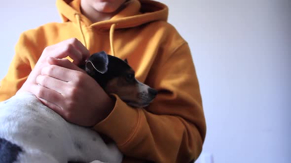 Millennial petting his little dog while they're sitting on a chair. alt