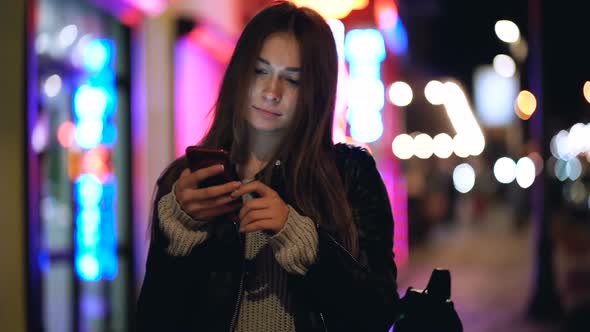 Woman Standing with Smartphone at The Evening Street