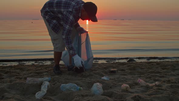 Cleaning Plastic Garbage Beach Man Collects Mud and Throws It Into a Bag alt