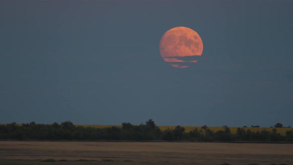 Rise of a Full Glowing Red Moon with Clouds Above the Horizon of the Earth alt