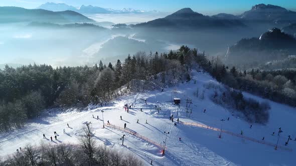 Aerial view of winter ski resort and skiers skiing down the slope. White winter in alpine scenery