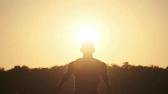 Silhouette of Young Man Jumping with Hands To the Side at Sunset. Slow Motion 240 Fps. alt