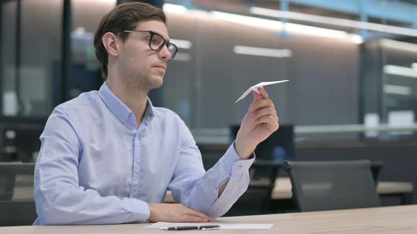 Young Man Holding Paper Plane in Office alt