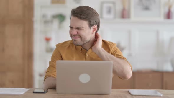 Young Man with Laptop having Neck Pain on Sofa alt