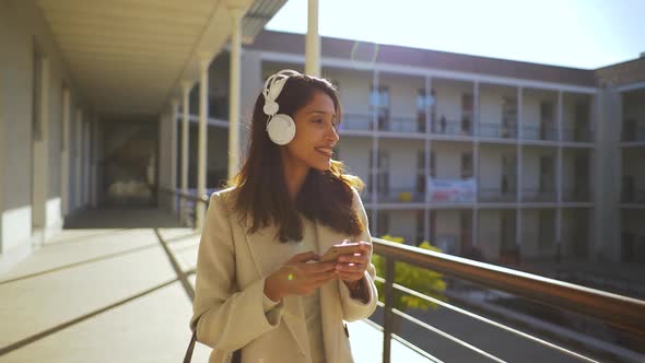 Slow motion shot of Indian woman with smartphone and headphones alt