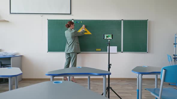 Teacher Near Blackboard Using Mobile Phone Video Camera Recording Herself on Learning Online Math alt