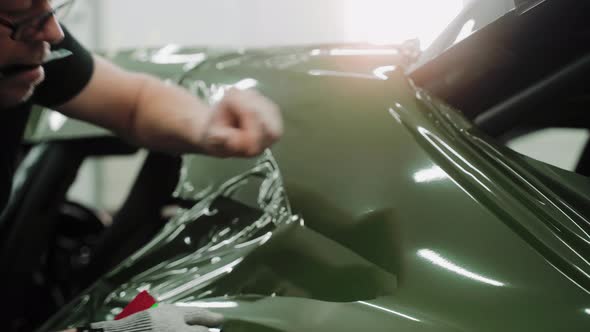 Man Vinyl Wrapping the Hood of the Car Smoothing Vinyl Film with His Fingers